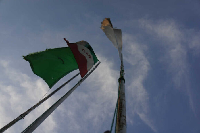 Iran's,Flag,With,The,Background,Of,Sky,And,A,Green