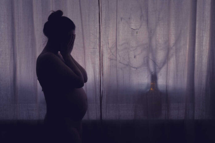 Young,Pregnant,Woman,Crying,With,Her,Hands,Folded,Near,Her