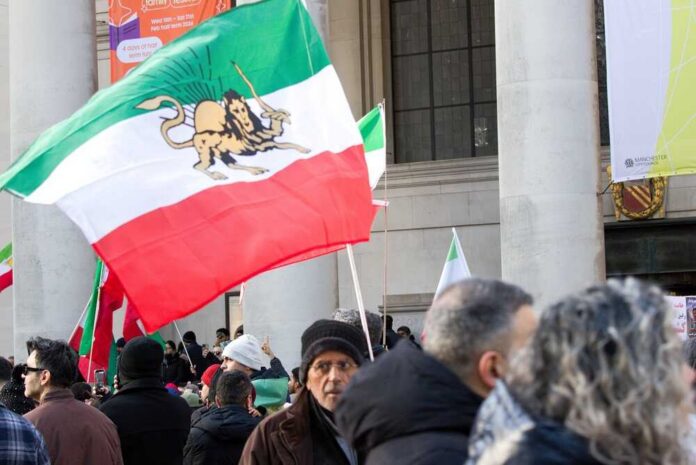 shutterstock_2730922323.jpg Crowd holding Iranian flags during a protest