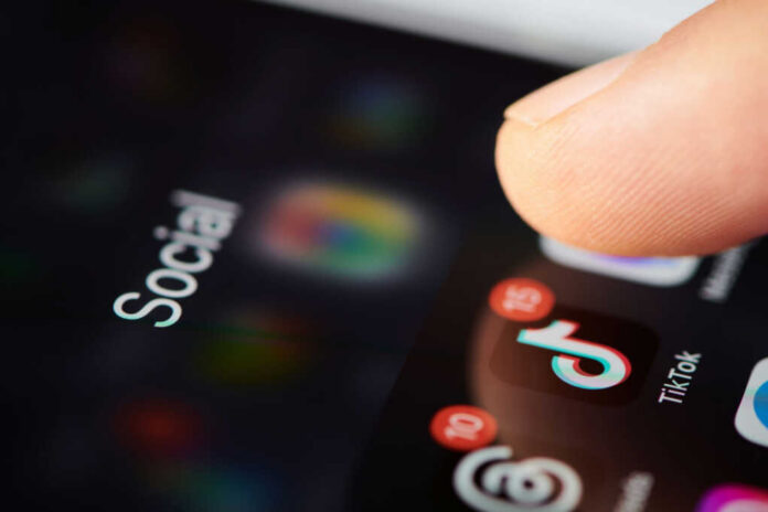shutterstock2452297177jpg Close-up of a finger tapping a TikTok icon on a smartphone screen with social media labels