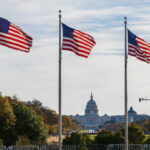 Three American flags waving in front of the Capitol building in Washington D.C.