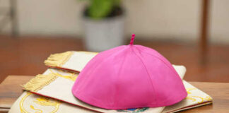 A pink ceremonial cap placed on a decorative cloth