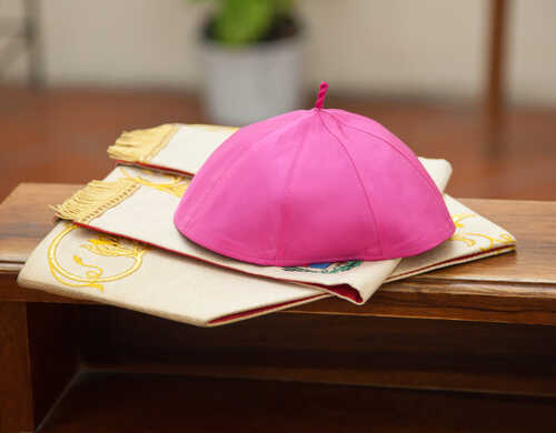 A pink ceremonial cap placed on a decorative cloth