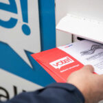 Person placing a mail-in ballot into a voting drop box
