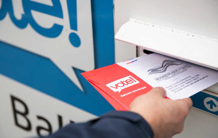 Person placing a mail-in ballot into a voting drop box