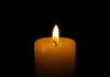 A lit candle with a soft flame against a black background