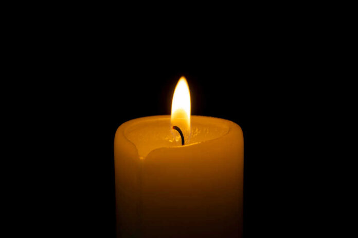 A lit candle with a soft flame against a black background