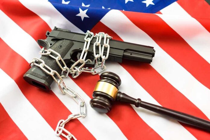 A handgun chained and placed on an American flag with a gavel nearby