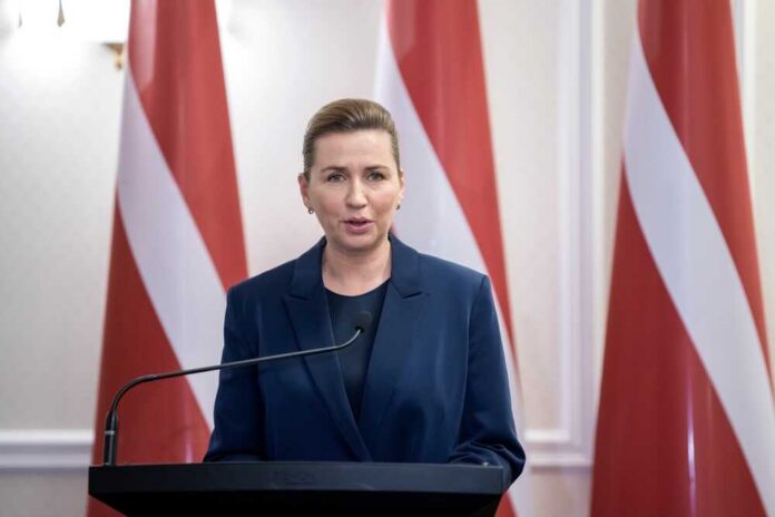 A female leader delivering a speech at a podium with Latvian flags in the background