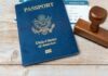 A U.S. passport, boarding pass, and a wooden stamp on a wooden surface