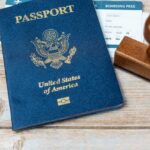 A U.S. passport, boarding pass, and a wooden stamp on a wooden surface