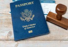 A U.S. passport, boarding pass, and a wooden stamp on a wooden surface