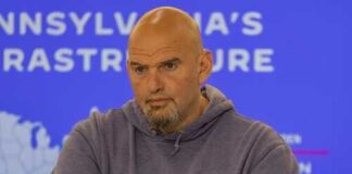 Man in a hoodie with arms crossed, looking serious in front of a presentation background