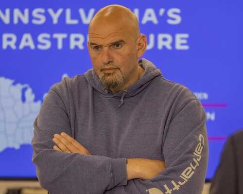 shutterstock_2322779359.jpg Man in a hoodie with arms crossed, looking serious in front of a presentation background