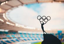 Silhouette of a figure holding Olympic rings against a stadium backdrop