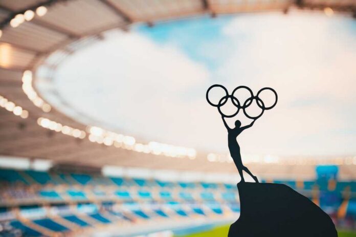 Silhouette of a figure holding Olympic rings against a stadium backdrop