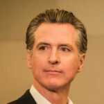 A man in business attire with a serious expression, captured in a medium shot