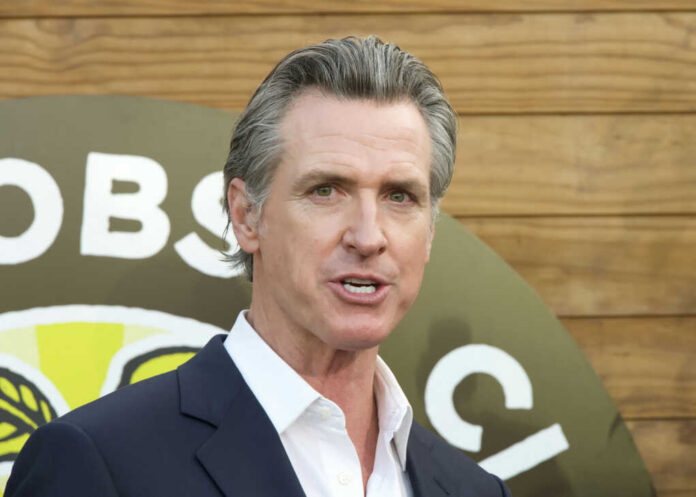 shutterstock_2386798227.jpg A man in a suit speaking at an outdoor event with a microphone