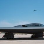 A B-2 stealth bomber on an airfield under a clear blue sky