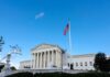 U.S. Supreme Court building with American flag and blue sky