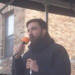 A man speaking into a microphone at an outdoor event