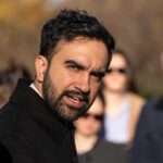 A man speaking passionately at an outdoor event with an engaged audience in the background