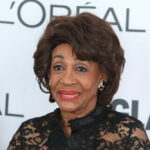 A woman in elegant black attire smiling at a celebrity event