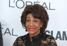 A woman in elegant black attire smiling at a celebrity event