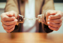 Close-up of hands holding handcuffs in a serious context