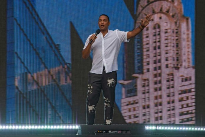 shutterstock2029189433jpg A speaker on stage holding a microphone with a city skyline in the background