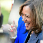 A woman smiling and engaging with a crowd at an outdoor event