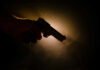Silhouette of a hand holding a handgun against a dramatic light background