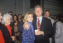 A couple posing together at a public event with a crowd in the background