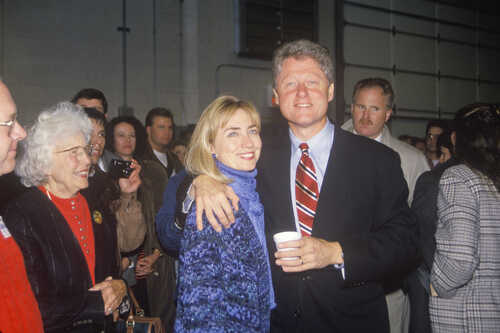 A couple posing together at a public event with a crowd in the background