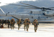 Marines in combat gear walking towards a helicopter