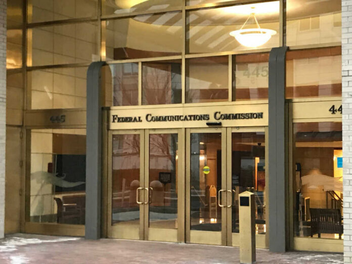 Entrance of the Federal Communications Commission building with glass doors and signage