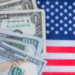 Various denominations of US dollar bills on an American flag background