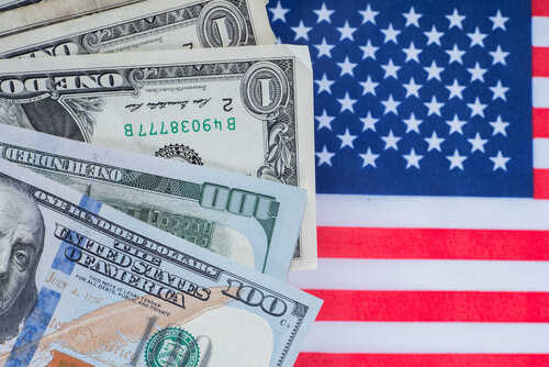 Various denominations of US dollar bills on an American flag background