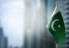 Flag of Pakistan waving in a blurred urban background