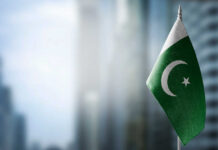 Flag of Pakistan waving in a blurred urban background