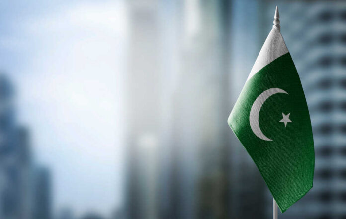 Flag of Pakistan waving in a blurred urban background