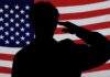 Silhouette of a person saluting in front of an American flag