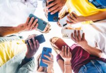 A group of friends holding smartphones in a circle, looking down at their devices