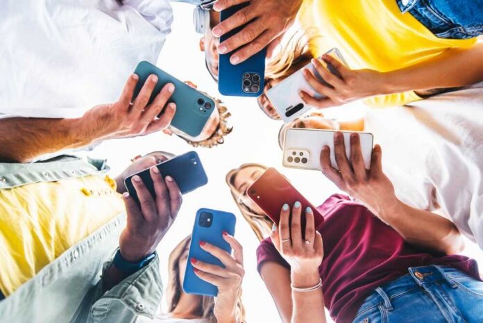 A group of friends holding smartphones in a circle, looking down at their devices