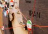 Strait Chaos: Iran Loses Mines, Sparks Global Risk Close-up of a wooden map highlighting Iran with travel pins and red strings