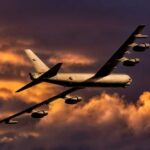 Military aircraft flying against a colorful sunset sky