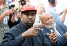 Kanye Banned? Mayor Battles Over Hate Speech A man wearing a red cap gestures during a discussion at a political event