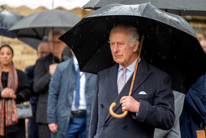 shutterstock_2282989513.jpg A man in formal attire holding an umbrella in the rain