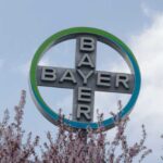 Bayer logo displayed on a sign surrounded by blooming flowers