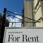 Sign indicating apartments available for rent against a blue sky